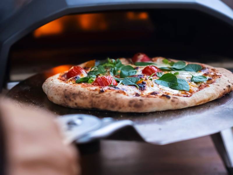 Larry's Pizza - Eine frisch gebackene Pizza wird aus dem ofen geholt